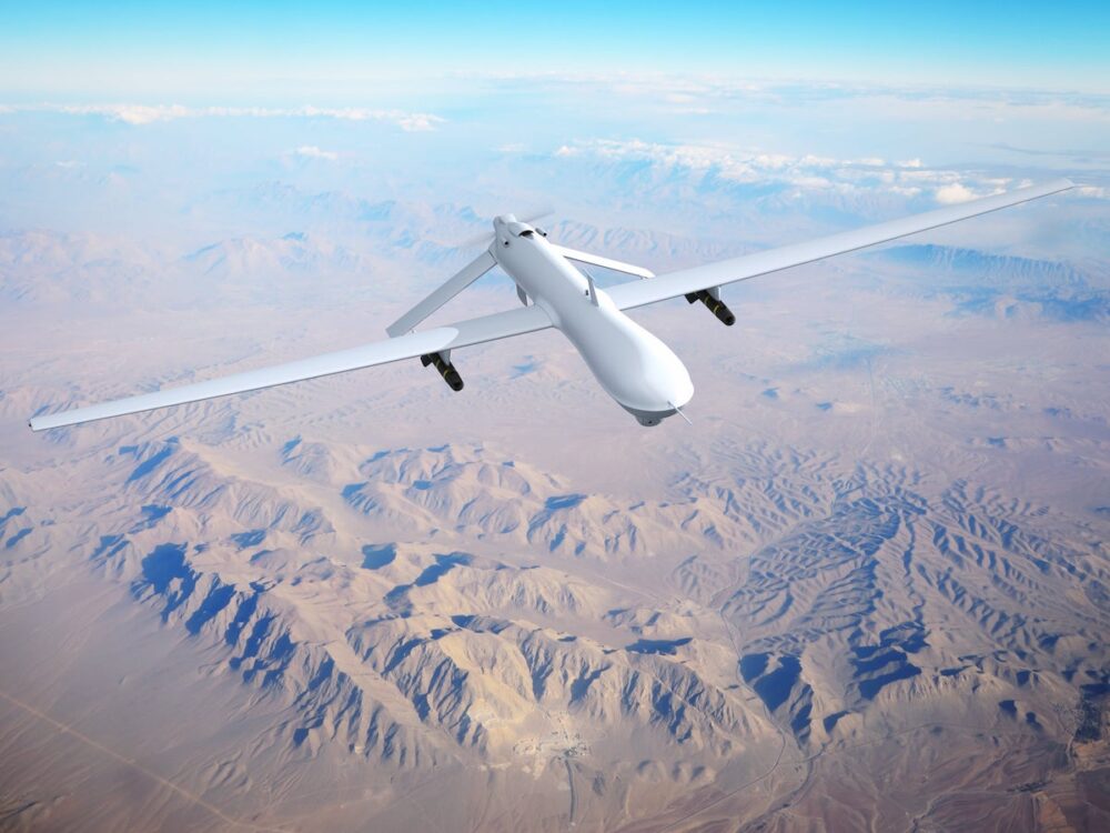 Military drone flies over a desert landscape