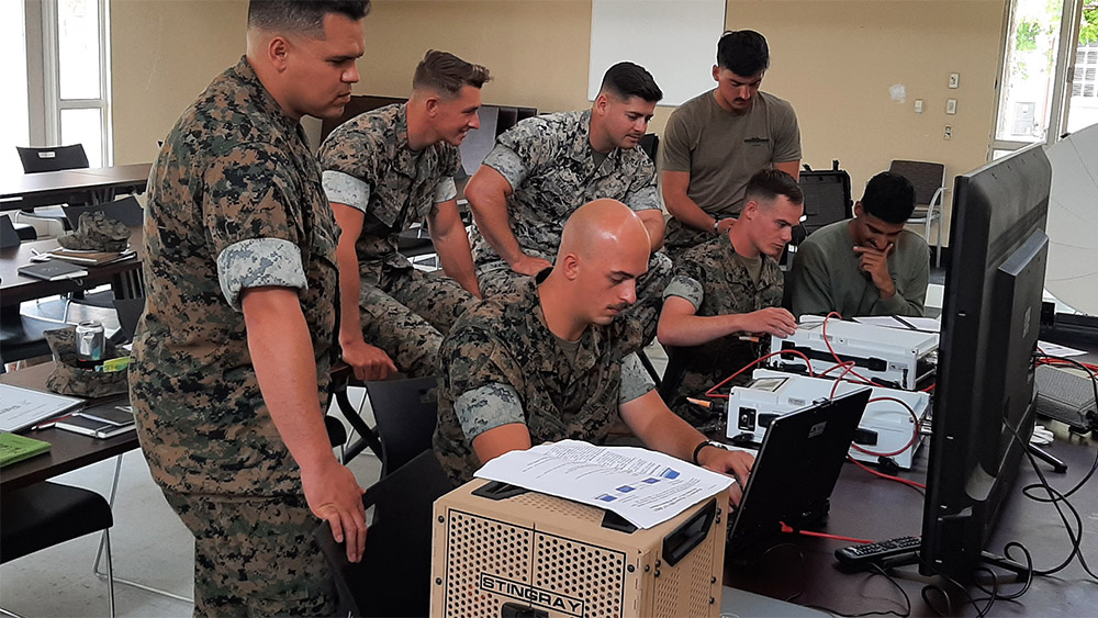 Soldiers in a classroom work with computer and communications equipment