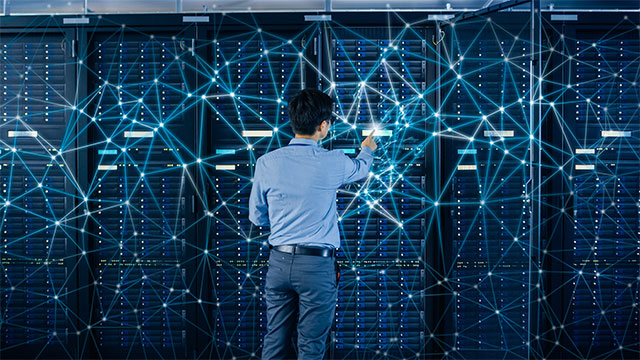 IT Engineer Standing Beside Open Server Rack Cabinets and Touching Digital Connections on a Server